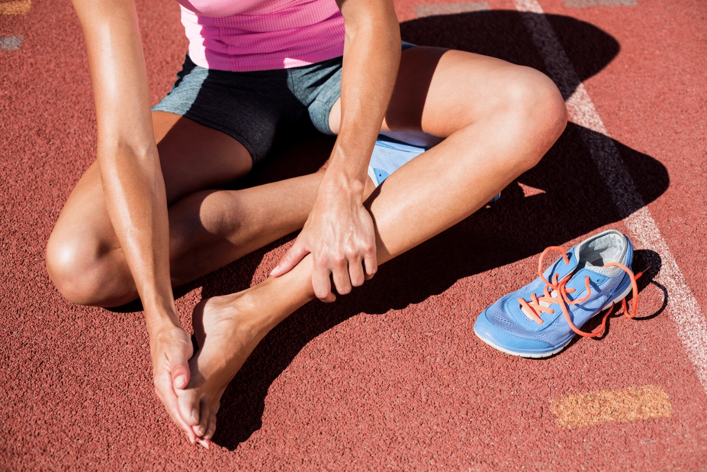 An athlete touches her foot, experiencing pain in the area.