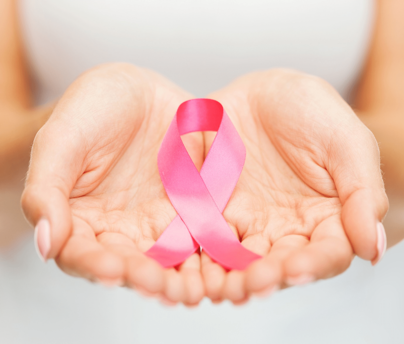The breast cancer ribbon cupped in a woman’s hands.