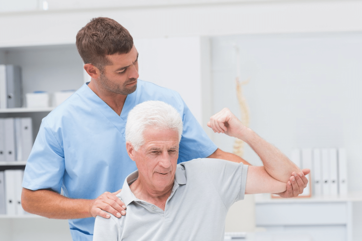 An older man works with his physical therapist in a clinic.