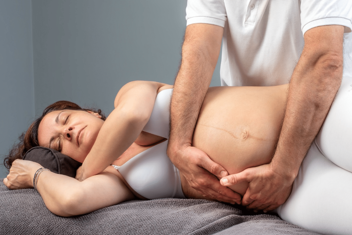 A physical therapist does massage therapy on a pregnant woman.