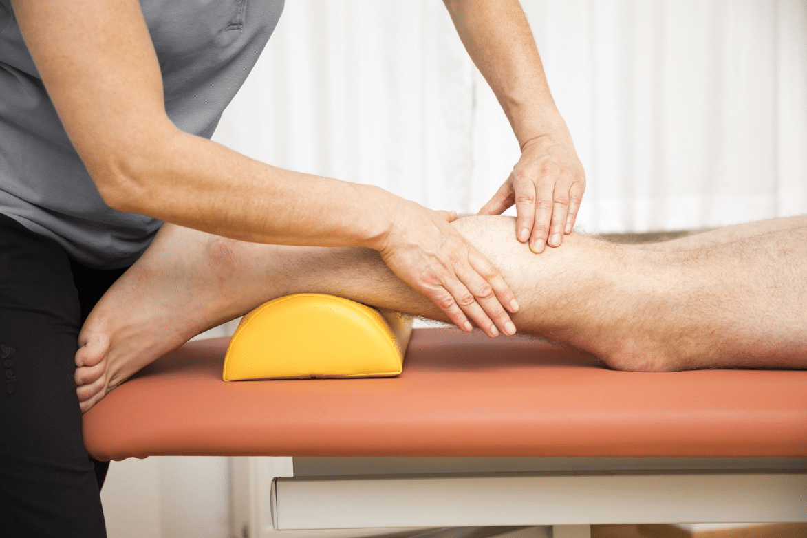 Physical therapy muscle stimulation being performed on client’s leg.
