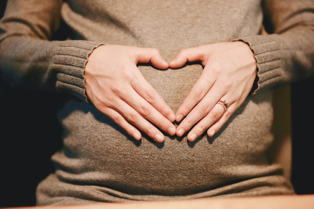 A pregnant woman posing with her hands on her belly